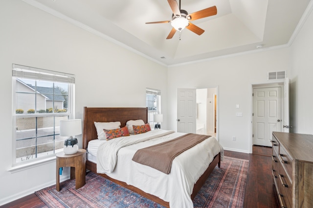 bedroom featuring a raised ceiling, dark hardwood / wood-style flooring, ceiling fan, and multiple windows