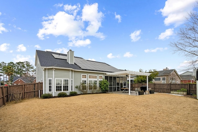 rear view of property featuring a pergola, a patio, and solar panels