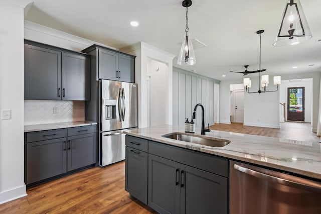 3806 Grateful Rd, North Charleston, SC 29420 - kitchen featuring appliances with stainless steel finishes, a sink, decorative backsplash, light stone countertops, and wood finished floors