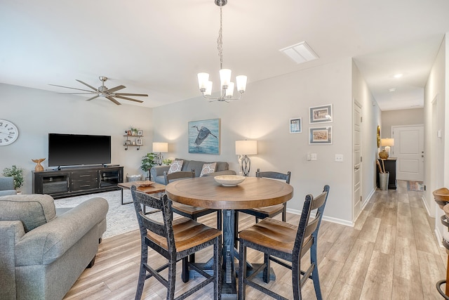 dining space with ceiling fan with notable chandelier, light wood-style flooring, and baseboards