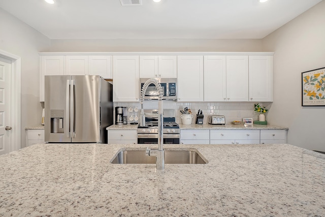 kitchen with light stone counters, visible vents, decorative backsplash, appliances with stainless steel finishes, and white cabinets