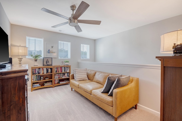 living area featuring a healthy amount of sunlight, light colored carpet, ceiling fan, and baseboards