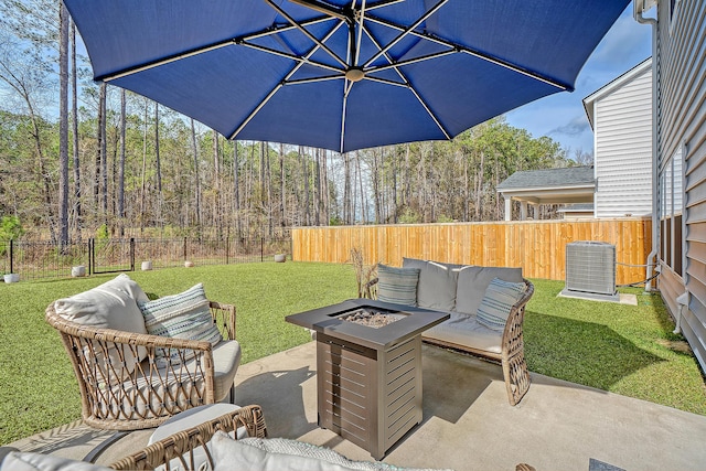 view of patio / terrace with central AC unit, a fenced backyard, an outdoor living space with a fire pit, and a view of trees