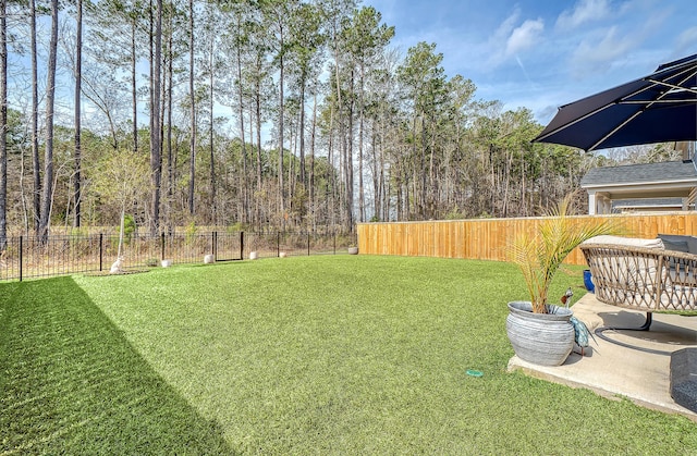 view of yard with a forest view and a fenced backyard