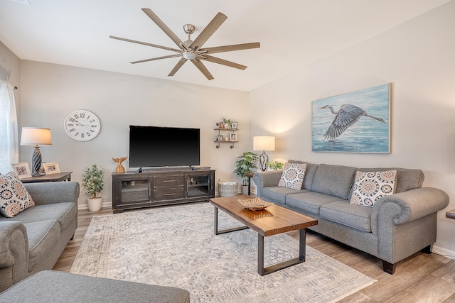 living room with ceiling fan, baseboards, and wood finished floors