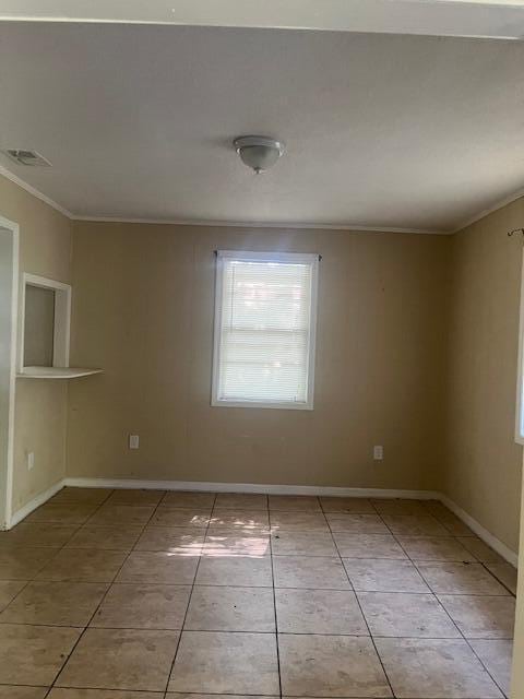 unfurnished room featuring ornamental molding and light tile patterned floors