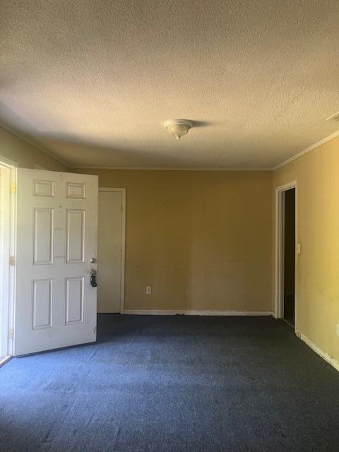 empty room with a textured ceiling and dark carpet