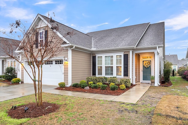 view of front of home with concrete driveway, a garage, and a shingled roof