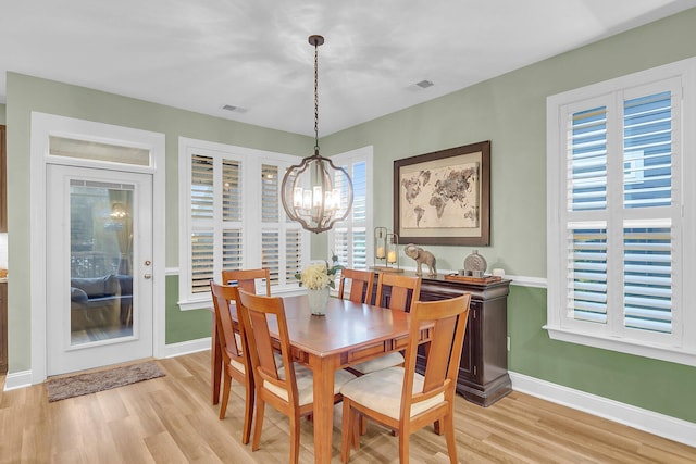 dining room with light wood-style flooring, visible vents, baseboards, and a chandelier