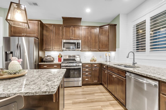 kitchen with light stone counters, visible vents, a sink, appliances with stainless steel finishes, and backsplash