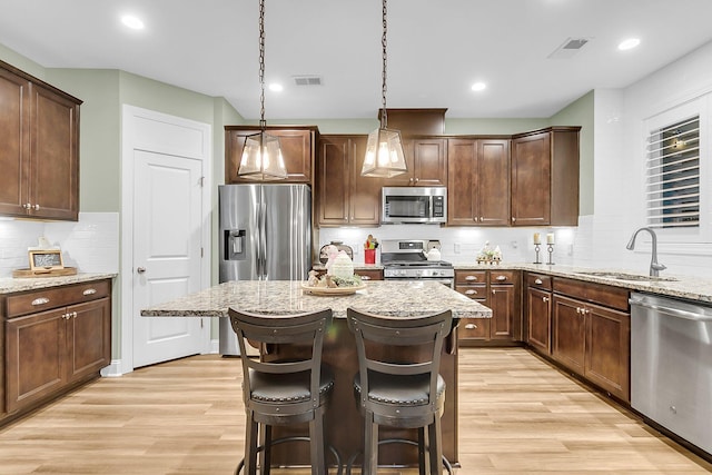 kitchen featuring a sink, stainless steel appliances, visible vents, and light wood-style flooring