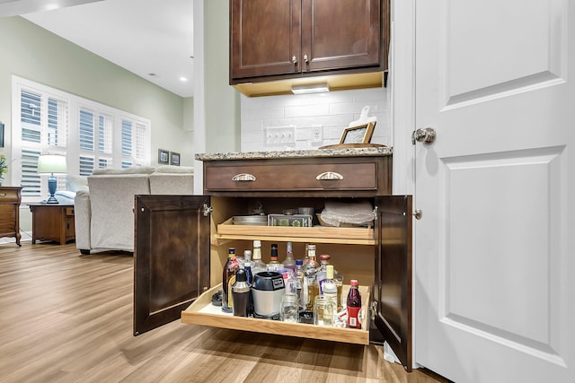 bar with light wood-type flooring and tasteful backsplash