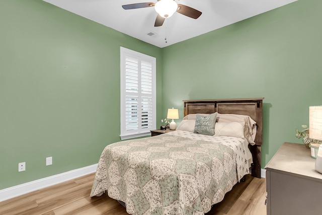 bedroom featuring visible vents, a ceiling fan, baseboards, and wood finished floors