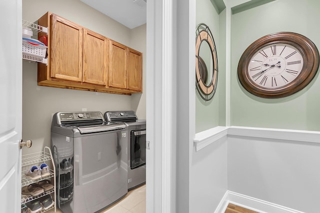 clothes washing area with baseboards, cabinet space, and independent washer and dryer