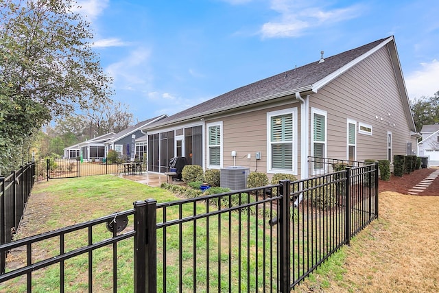 rear view of house featuring a fenced backyard, cooling unit, a yard, a sunroom, and a patio area