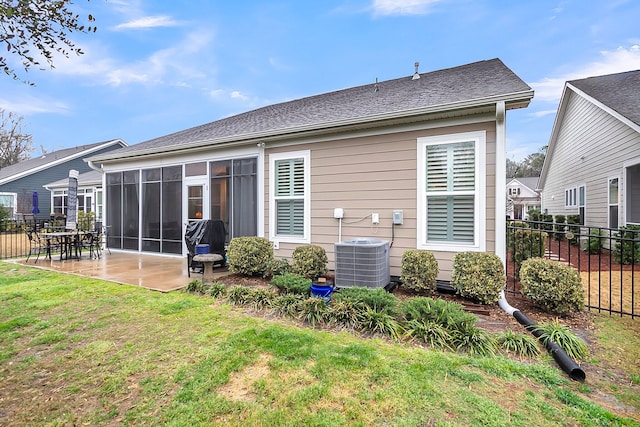 rear view of house with a lawn, central AC, fence, a sunroom, and a patio area