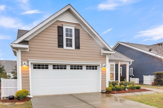 traditional home with concrete driveway, fence, central AC, and a shingled roof