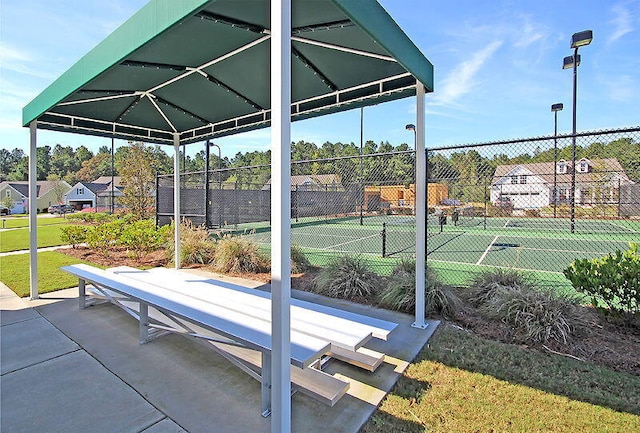 view of community with a tennis court and fence