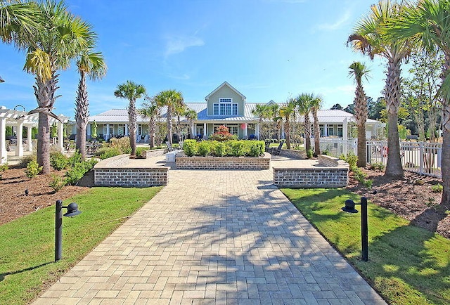 view of front of home featuring decorative driveway, fence, a front lawn, and a pergola