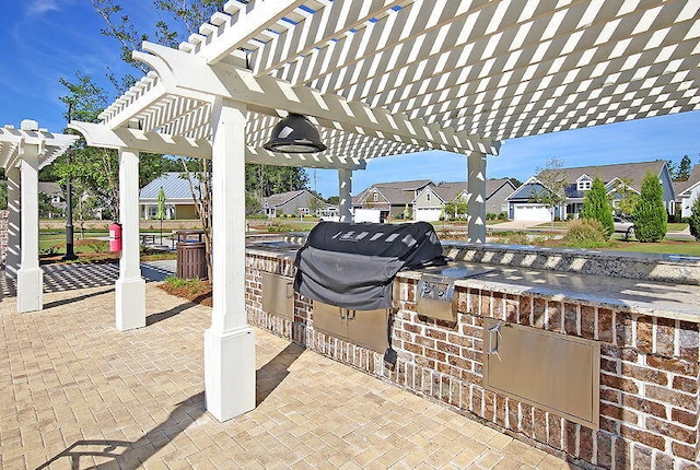 view of patio / terrace featuring a residential view, a grill, an outdoor kitchen, and a pergola