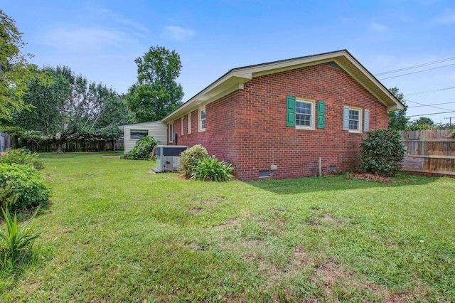 view of side of property featuring a yard, crawl space, brick siding, and fence