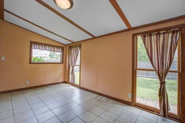 spare room with a wealth of natural light, light tile patterned flooring, and vaulted ceiling with beams