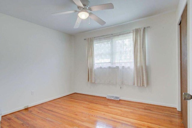 empty room with baseboards, a ceiling fan, visible vents, and light wood-style floors