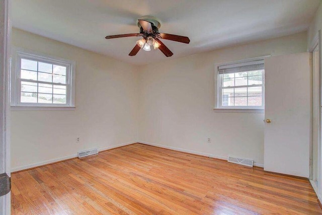 unfurnished room with light wood-style floors, visible vents, and a wealth of natural light