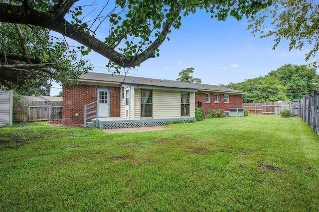 rear view of house featuring brick siding, a lawn, and a fenced backyard