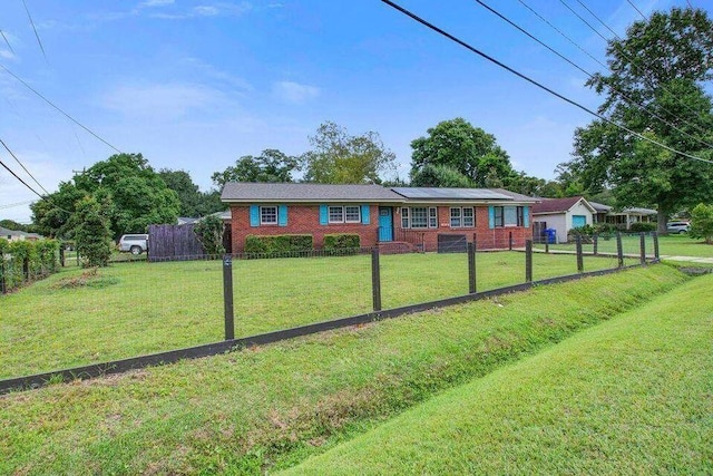 ranch-style home featuring brick siding, a front yard, fence private yard, and roof mounted solar panels