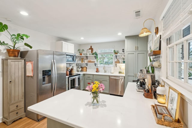 kitchen featuring visible vents, appliances with stainless steel finishes, hanging light fixtures, light countertops, and a sink