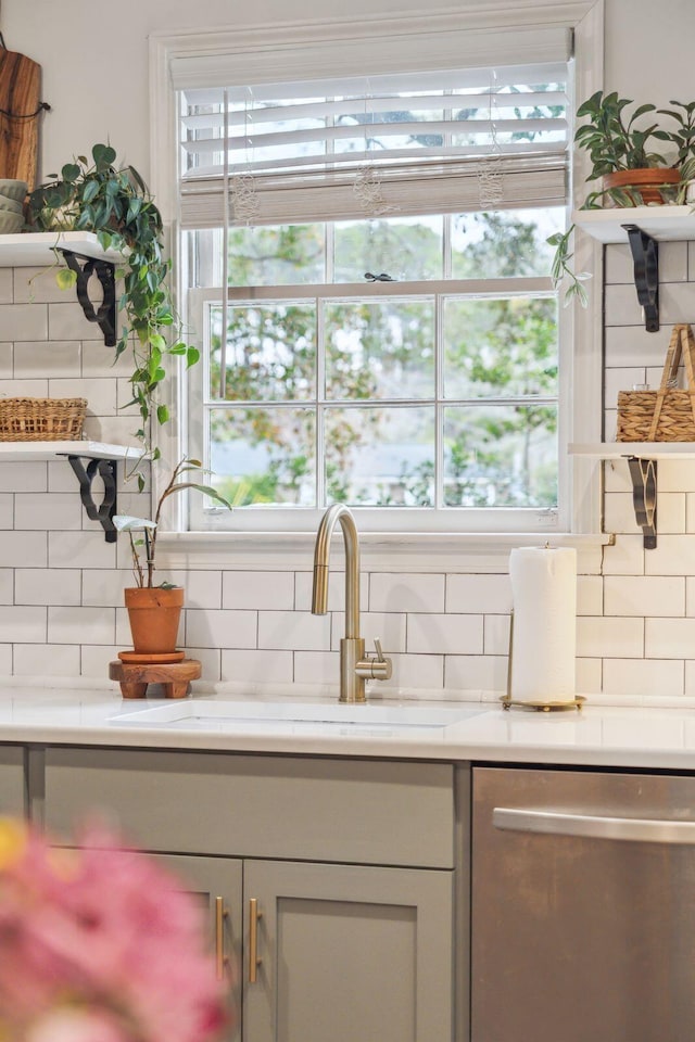 kitchen featuring tasteful backsplash, a sink, stainless steel dishwasher, and light stone countertops