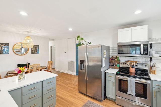 kitchen with tasteful backsplash, light countertops, hanging light fixtures, visible vents, and appliances with stainless steel finishes