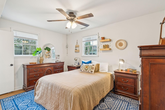 bedroom featuring a ceiling fan, visible vents, and wood finished floors