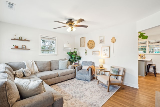 living room with a ceiling fan, baseboards, visible vents, and wood finished floors