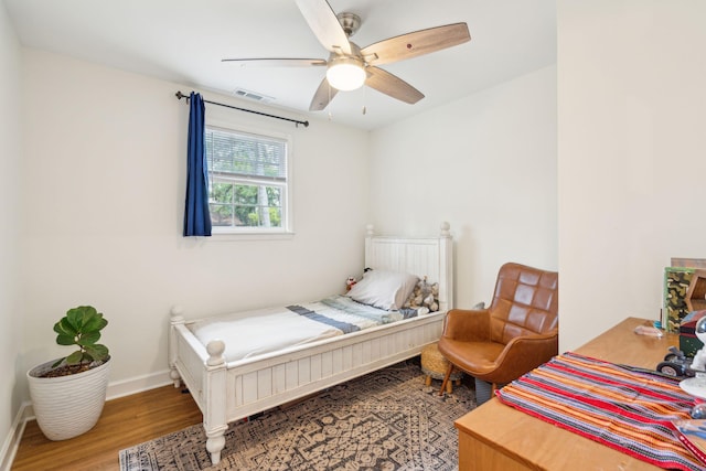 bedroom featuring a ceiling fan, baseboards, visible vents, and wood finished floors