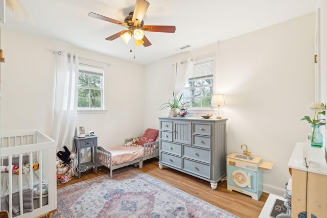 bedroom featuring visible vents, ceiling fan, baseboards, and wood finished floors