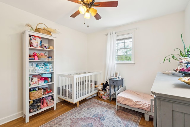 bedroom with ceiling fan, wood finished floors, and baseboards