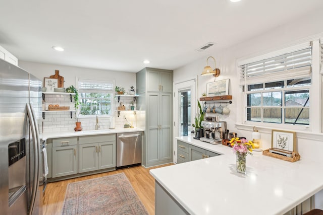 kitchen with visible vents, stainless steel appliances, light countertops, open shelves, and backsplash