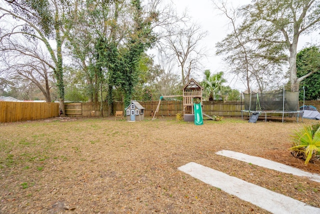 view of yard with a trampoline, a playground, and a fenced backyard