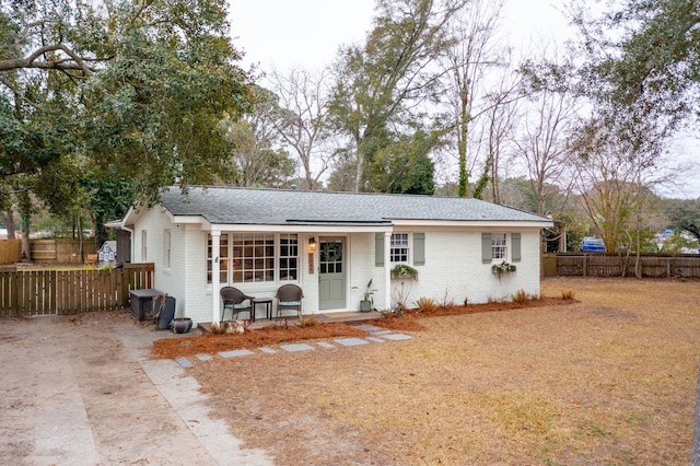 single story home featuring brick siding, roof with shingles, and fence