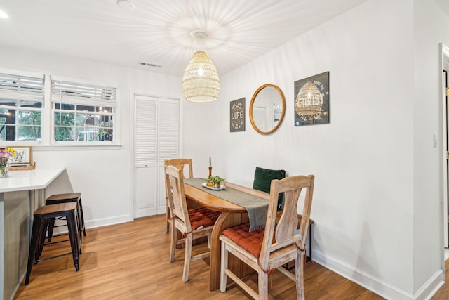 dining space with light wood-style flooring, visible vents, and baseboards