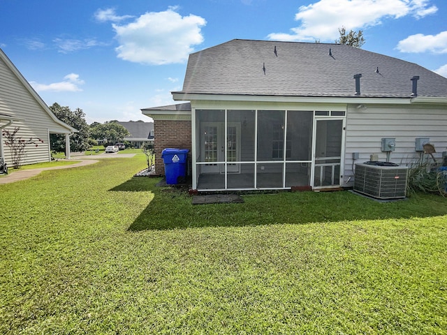 back of property with a sunroom, central AC unit, and a lawn