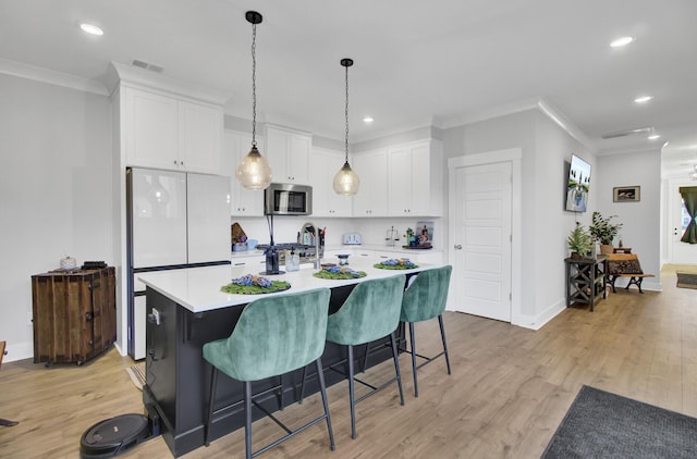 kitchen featuring ornamental molding, a center island with sink, white cabinets, and light wood-type flooring