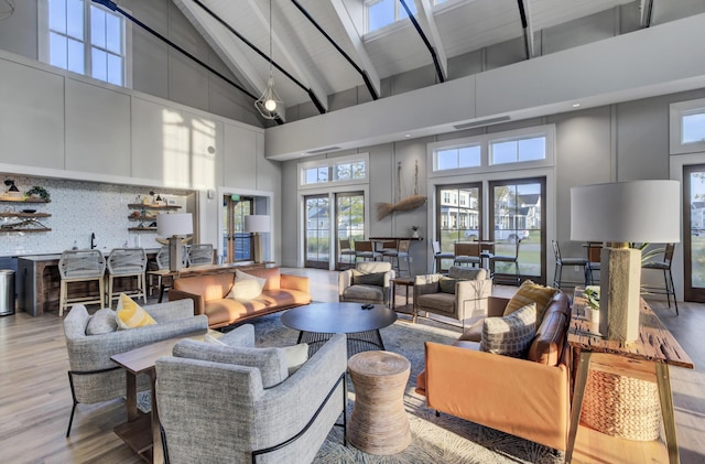 living room featuring beamed ceiling, light wood-type flooring, high vaulted ceiling, and french doors