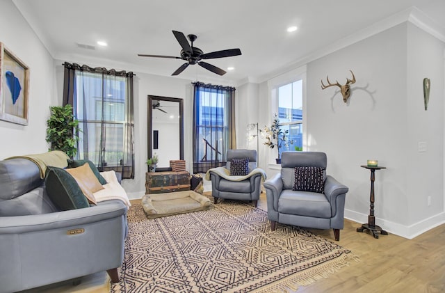 living room with crown molding, ceiling fan, and light wood-type flooring