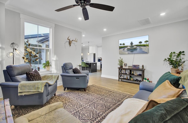 living room with crown molding, ceiling fan, and light wood-type flooring