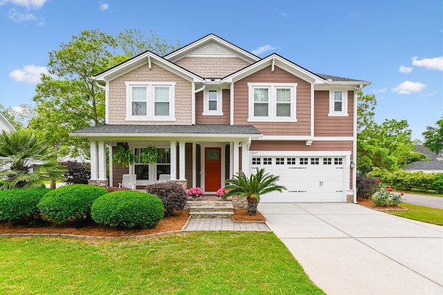 craftsman inspired home with an attached garage, concrete driveway, covered porch, and a front lawn