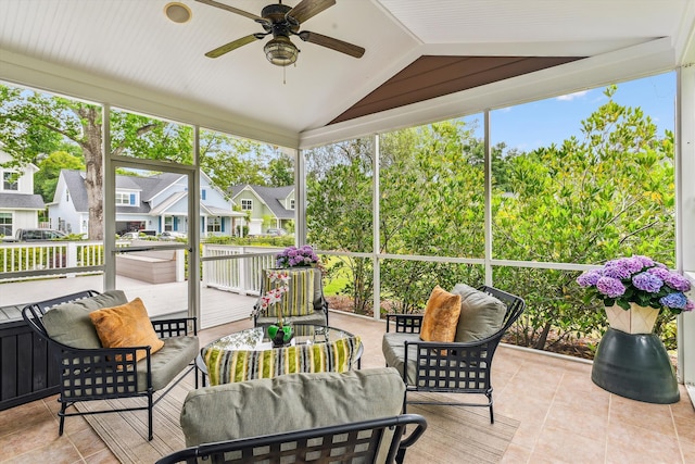 sunroom featuring ceiling fan, an outdoor hangout area, vaulted ceiling, and a residential view