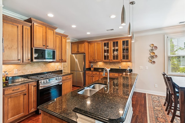 kitchen featuring appliances with stainless steel finishes, a sink, ornamental molding, brown cabinetry, and baseboards